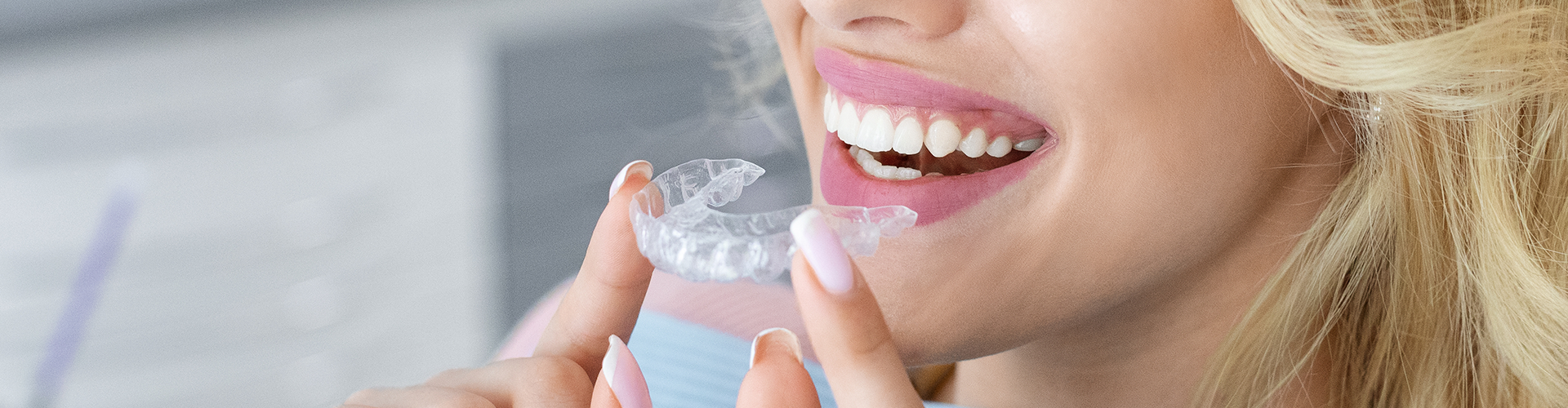 Woman putting clear aligner in mouth.